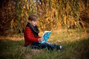 A boy reading a book - How to Foster a Love of Reading in Young Children - Queens Grove School